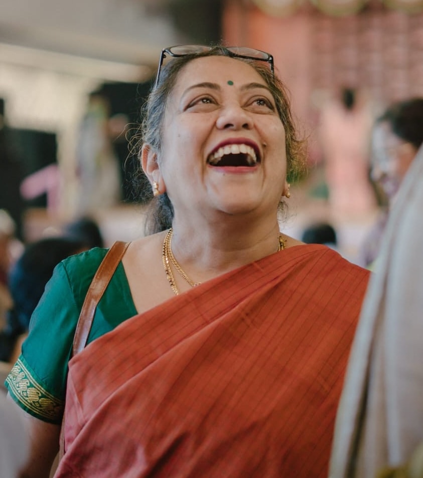 photo of anuradha kiran smiling in a red sari and green blouse.